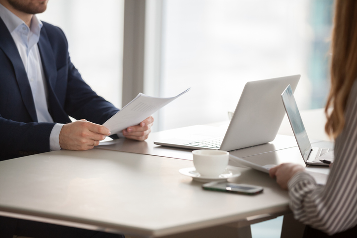 Close up of business partners hold documents or papers considering contract terms, diverse workers or colleagues discuss agreement condition talk or negotiate at meeting in office. Partnership concept